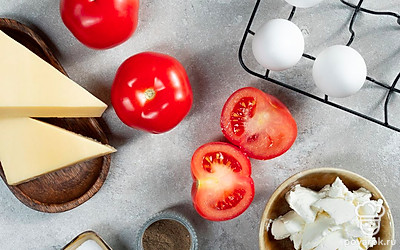 Помидоры помойте, удалите плодоножки, срежьте верхнюю часть и аккуратно ложкой и ножом извлеките мякоть. Куриное яйцо помойте. Пармезан натрите на терке. Базилик для подачи вымойте, обсушите, отделите листики от стебельков. Противень застелите пергаментной бумагой. Разогрейте духовку до 180 градусов. Подготовьте миксер.