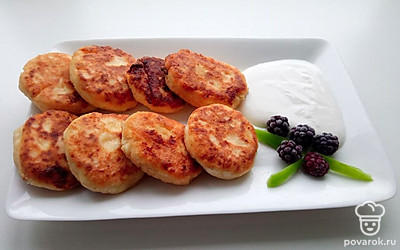 Выложите сырники на тарелку и украсьте их ягодами.