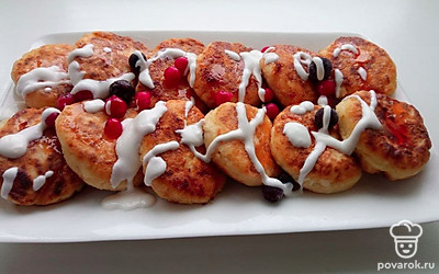 Сырники выложите на блюдце и налейте на них сметану, сверху насыпьте ягоды.