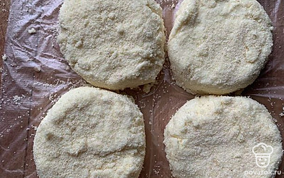 Начните формовать сырники. Доску присыпьте манкой, возьмите порцию массы размером примерно со столовую ложку и обваляйте в крупе со всех сторон. Выложите на посыпанную доску и формируйте каждый сырник стаканом.