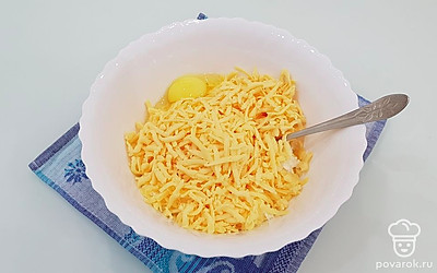 К творогу добавьте натертый на крупной терке сыр и яйцо.