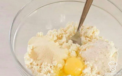 В миску с творогом положите сахар, манку и яйцо, всё тщательно перемешайте.