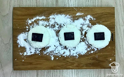 Из каждого шарика сформируйте лепешку, на которую положите по квадратику шоколада.