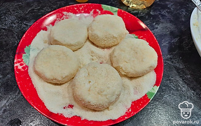 Каждую творожную лепёшку обваляйте в манной крупе со всех сторон.
