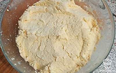 Добавьте сахар, разрыхлитель и муку. Сахар и муку берите из расчёта 2 столовые ложки на 200 г творога. Перемешайте, получится плотное тесто.