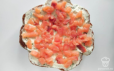 Выложите еще один слой хлеба, мелко накрошите петрушку, перемешайте с оставшимся сыром и смажьте половиной массы второй корж. Срежьте с семги неровные края, измельчите их кубиком и выложите кусочки на сыр. Самую толстую и мясистую часть оставьте для украшения верхнего слоя.