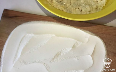 На разделочную доску выкладываем 3 столовые ложки муки и выкладываем массу на муку.