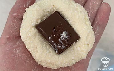 Сформировать сырник и положить в него дольку шоколада, затем обжарить с двух сторон на кокосовом масле на среднем огне.