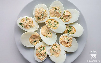 Удалите желтки из яиц и поместите их в миску. Добавьте к желткам сметану, сок лимона и зеленый лук, слегка посолите и перемешайте. Выложите смесь обратно в белки и накройте красной икрой.