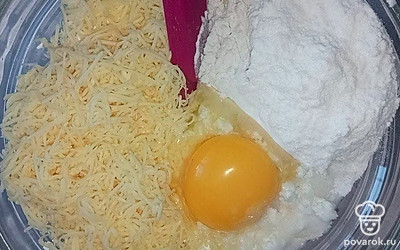 Подготовьте небольшую емкость, смешайте в ней творог, вбейте яйцо, взбейте до однородной массы. Сыр натрите на мелкой терке, к творожной консистенции добавьте муку, соль, тертый сыр.