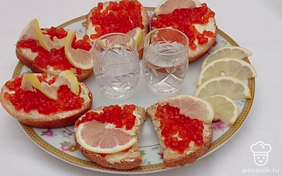 Налейте водку в стакан и закусывайте ее вкуснейшим бутербродом с икрой и кислым лимоном.