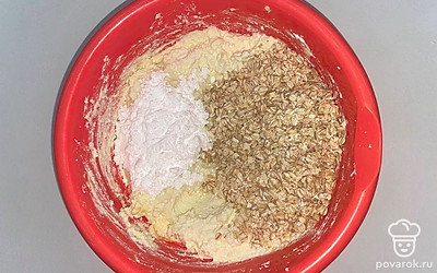 Разложите творог в миску, к нему вбейте яйца, добавьте сахарную пудру и половину овсяных хлопьев. Всю консистенцию размешайте до однородной массы.