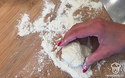 Присыпьте доску мукой и наберите 1 столовую ложку с горкой творога. Обваляйте комочек творога со всех сторон в муке и сделайте шарик.