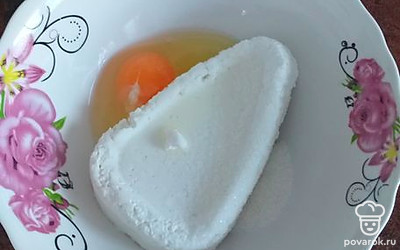 В емкость выложите творог, сахар, яйцо. Тщательно разомните вилкой до получения однородной массы.