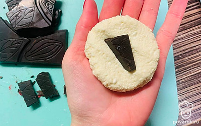 Сформируйте в руке лепешку из теста, в середину поместите кусочек шоколада. Сделайте из теста шарик и придавите его рукой.