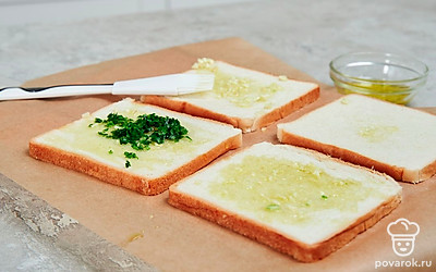 Подготовьте ломтики хлеба. Одну сторону каждого куска хлеба натрите измельченным чесноком, солью и сбрызните оливковым маслом с помощью кулинарной кисти. Сверху посыпьте ломтики мелко нарезанной петрушкой.