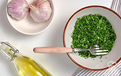 Сделайте начинку. В миску сложите нарезанную зелень и измельченный чеснок. Добавьте растительное масло и перемешайте.