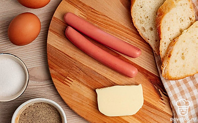 Нарежьте хлеб ломтиками. Сосиски очистите от упаковки. Отрежьте кусочек сливочного масла. Подготовьте яйца.