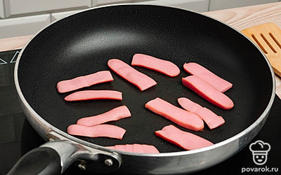 На сливочном масле в сковороде обжарьте полоски из сосисок с каждой стороны до легкой корочки. Снимите сосиски со сковороды.
