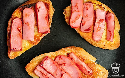 Переверните гренку и обжарьте с другой стороны также 3 минуты. Сверху на гренку выложите сосиски.