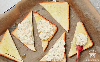 Сделайте тосты. На противень уложите пергамент. Выкладывайте кусочки хлеба, оставляя между ними небольшое расстояние. Поверх хлеба положите сырную начинку толстым слоем. Поставьте сырные тосты в разогретую духовку на 5-6 минут, запекайте до золотистой корочки.