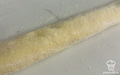 Насыпьте на стол немного муки и раскатайте тесто в длинную «колбаску».