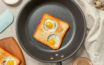 Приготовьте тосты. Разогрейте на сковороде масло, выложите на нее ломтики хлеба. Через пару минут переверните тосты, уменьшите огонь до минимума и в каждое отверстие вылейте по одному яйцу. Посолите, поперчите. Накройте крышкой и жарьте тосты в течение 2-3 минут до готовности.
