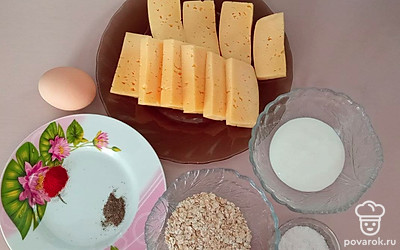 Сыр нарежьте на равные бруски и положите в тарелку, а яйцо положите на стол. Овсяные хлопья разместите в глубокой емкости, душистый перец и паприку насыпьте на тарелку, сливки поместите в тару, а соль насыпьте в емкость.