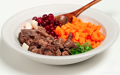 Завершите приготовление. Отделите белки от желтков. Мелкими кубиками нарежьте белки, морковь, мясо. Смешайте ингредиенты. На дно формы для кексов выложите кинзу, клюкву, смесь овощей, мяса и белка. Залейте горячим бульоном. Остудите. Уберите в холодное место на 5-6 часов минимум.