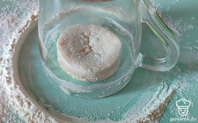 На рабочую поверхность просеять 2 столовые ложки муки. Разделить тесто на равные части. Каждый кусочек теста обвалять в муке и с помощью стакана придать округлую форму сырникам. Крутить стакан. Тесто, ударяясь об стакан, принимает округлую форму.