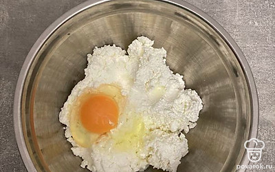 Творог переложите в миску. Добавьте к нему яйцо.