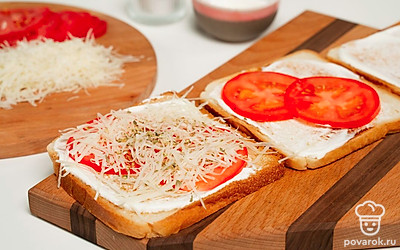 Соберите тост. Обжарьте кусочки хлеба с двух сторон на сухой сковороде до румяной корочки. Намажьте сметану на хлеб с одной стороны. Далее положите кружочки помидоров и немного посолите. Сверху присыпьте сыром и орегано.