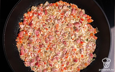 Добавьте в сковороду сметану. Перемешайте и тушите овощи с сосисками до готовности в течение 10-15 минут.