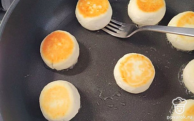 Аккуратно переверните, подцепив тонкой лопаткой или вилкой. Жарьте с другой стороны еще 3 минуты под крышкой, чтобы сырники пропарились внутри. 