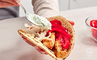 Соберите гирос. В середину питы положите сначала мясо, затем свежий лук, помидор и болгарский перец. Сверху полейте соусом и заверните гирос.