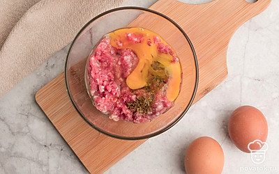 В подходящую по размеру емкость поместите фарш и разбейте одно яйцо. Посолите и добавьте специи на свой вкус, перемешайте.