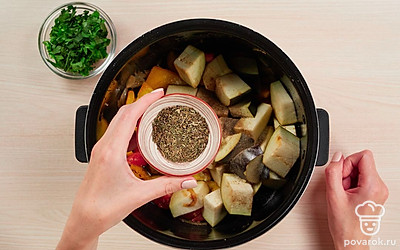 Добавьте баклажаны. Баклажаны отожмите от жидкости и положите в чашу мультиварки. Чеснок добавьте к овощам. Всыпьте соль, перец и сушеный базилик. Перемешайте, накройте крышкой и включите программу «Тушение» на 25 минут.