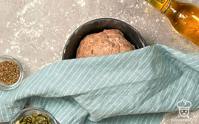 Приступите к замесу теста. В чашу комбайна насыпьте пшеничную и полбяную муку, овсяные хлопья, душицу, тыквенные семечки. Влейте дрожжевую смесь, оставшуюся воду, уксус. Включите прибор на малые обороты, через 1-2 минуты посолите, вымешивайте 5 минут. Влейте горчичное масло, переключите прибор на среднюю скорость и мешайте еще 5 минут. Переложите тесто в миску, затяните пищевой пленкой, оставьте для подъема на 30-40 минут.