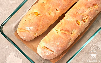 Сформируйте изделия. Тесто разделите на две части. Вытяните и раскатайте на столе, придав изделиям продолговатую форму. Положите багеты на противень, прикройте полотенцем и оставьте на 15 минут. Затем припылите их мукой и сделайте несколько надрезов по диагонали. Включите духовку на 195 градусов, создайте паровую баню при помощи емкости с жидкостью. После разогрева поставьте противень на среднюю полку духовки на 15 минут.