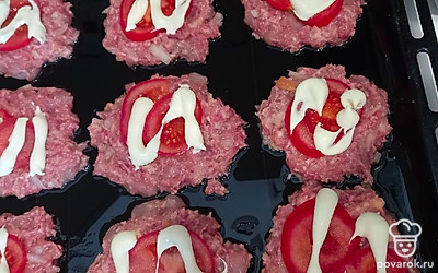 Противень смазать подсолнечным маслом и выложить на него сформированные котлеты, сверху положить дольки помидора и покрыть майонезом. 