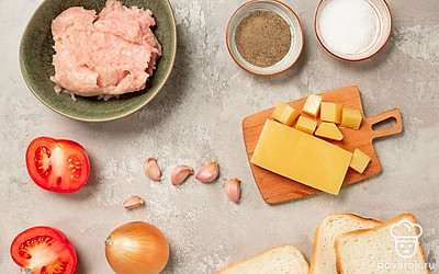 Подготовьте необходимые продукты. Зубчики чеснока почистите, вымойте и пропустите через пресс. Лук почистите, вымойте и мелко нарежьте. Сыр натрите на терке. Помидор вымойте и нарежьте кружочками. Зелень вымойте и обсушите. Приготовьте противень и пекарскую бумагу. Разогрейте духовку до 190-200 градусов.