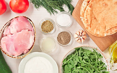 Подготовьте лепешки — слегка поджарьте их на сковороде без масла и оставьте остывать под полотенцем. Куриное мясо отделите от кости и кожи, промойте. Вымойте огурец и помидоры, очистите от шелухи чеснок. Промойте веточки укропа.Очистите огурец от кожуры, мелко нарежьте или натрите на терке.Измельчите укроп, чеснок пропустите через пресс.Помидоры нарежьте дольками, а рукколу порвите руками.