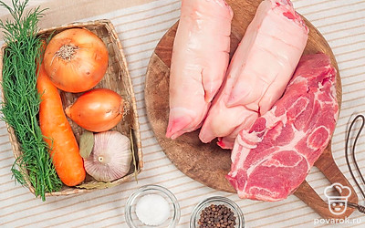 Мясо и свиные ножки хорошо вымойте. При необходимости опалите волоски. Вымочите ноги в холодной воде в течение нескольких часов. Периодически меняйте воду на свежую. Овощи почистите и помойте. Зелень промойте и измельчите по отдельности. Морковь для украшения фигурно нарежьте.