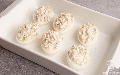 В половинки яиц аккуратно поместите начинку. Выложите яйца в форму для выпекания. Запейте в заранее разогретой до 180 градусов духовке в течение 10 минут.