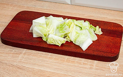 На разделочной доске нарежьте пекинскую капусту квадратами.