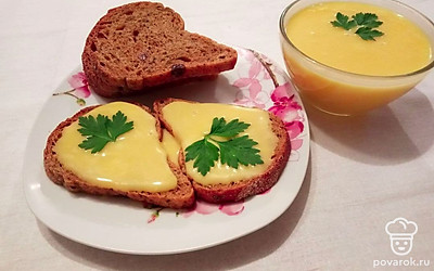 Намажьте плавленый сыр на хлеб и сверху разместите немного зелени.