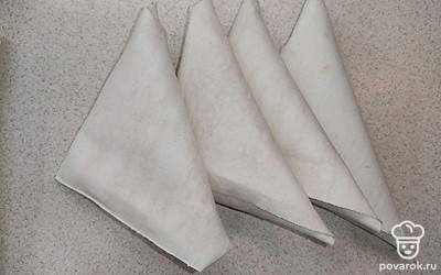 Порежьте лаваш на полосы по несколько сантиметров. Обрежьте закругленные края полосок лаваша, чтобы они приняли квадратную форму, так удобней будет придать лавашу треугольную форму. На каждую полоску лаваша выложите 1 ст.л. начинки, затем немного прижмите начинку, распределяя ее в основании полосы в форме треугольника. После заверните лаваши в треугольники.