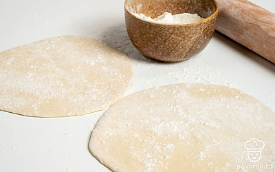 Сделайте заготовки для багетов. Увеличившееся в объеме тесто разделите на две части. Каждую раскатайте в пласт толщиной 0,7-1 см. Присыпьте их мукой и каждый не плотно сверните в рулет.