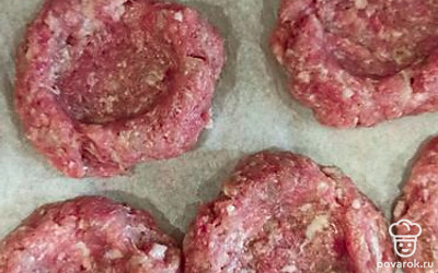 Из фарша скатать шарики, выложить на противень, придавить и в центре сделать углубление.