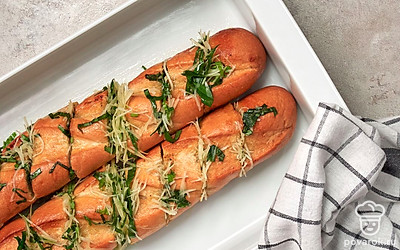 Приготовьте багет с твердым сыром. В батоне сделайте глубокие надрезы. Заполните их сыром с зеленью. Затем поместите багет с сыром в форму, закройте крышкой и поставьте в духовку на 10 минут при температуре 200 градусов. Снимите крышку, присыпьте багет 1 ст. л. сыра и еще на 5 минут поставьте в духовку.